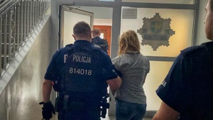 policjanci prowadzą zatrzymaną kobietę