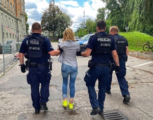 policjanci prowadzą zatrzymaną kobietę