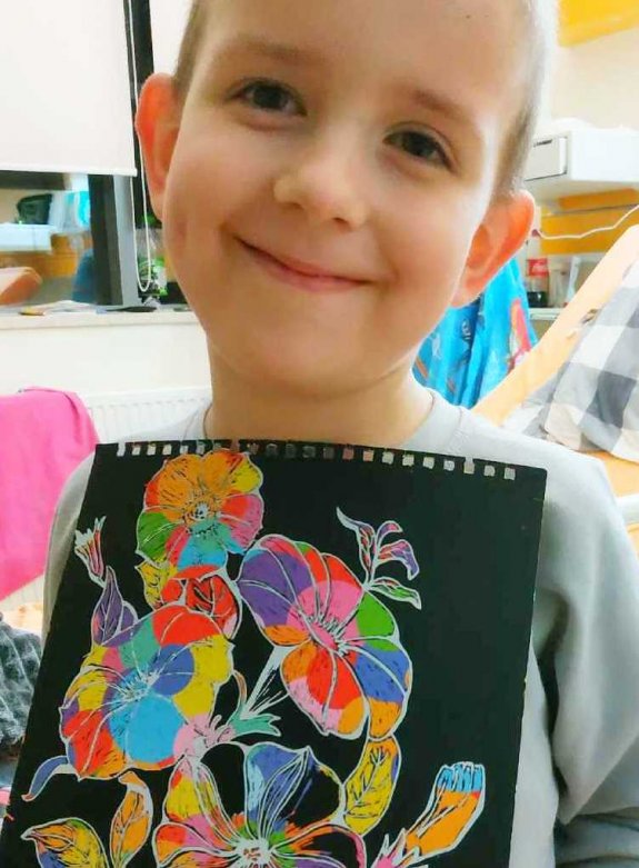 chłopiec z laurką przedstawiającą motyw kwiatów