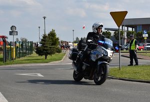 Policjant na motocyklu pilotuje peleton wybiegający ze stadionu .