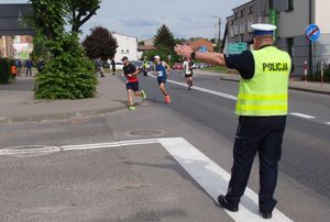 Policjant drogówki wskazuję wskazuję kierunek biegu trzem biegaczom