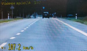Widok z ekranu policyjnego wideorejestratora. Droga jednojezdniowa dwukierunkowa. W tle ciemny samochód.
Na dole kadru wyświetlona prędkość 107.2 km/h.