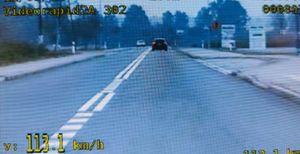 Widok z ekranu policyjnego wideorejestratora. Droga jednojezdniowa dwukierunkowa. Na jezdni linia podwója ciągła. W tle ciemny samochód widziany z tyłu oraz jasny jadący z przeciwnego kierunku.
Na dole kadru wyświetlona prędkość 113.1 km/h.