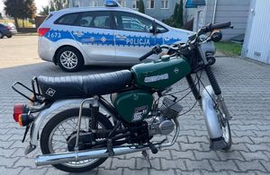 Odzyskany przez policjantów zielony motorower simson. W tle policyjny radiowóz.