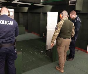 Policjanci na strzelnicy zamkniętej, stoją przy kulochwycie.