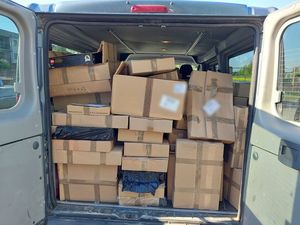 Zdjęcie w kolorze, przedstawia wnętrze samochodu typu bus wypełnione kartonami.
