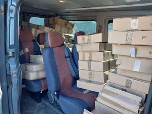 Zdjęcie w kolorze przedstawia wnętrze pojazdu typu bus wypełnione kartonami.