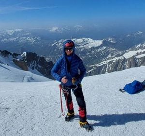 Alpinista stoi na szczycie Mont Blanc w tle widok na Alpy.