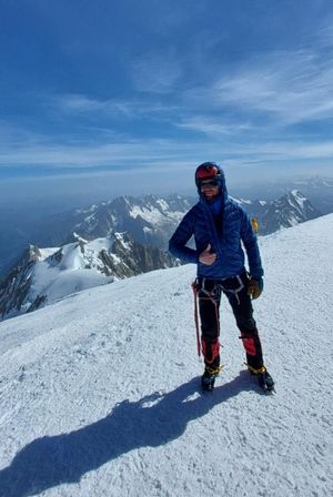 Alpinista na szczycie Mont Blanc. W tle ośnieżone szczyty Alp.