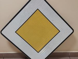 Zdjęcie w kolorze przedstawia znak drogowy D-1 oparty o posadzkę i ścianę.