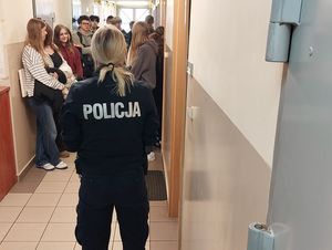 Zdjęcie w kolorze przedstawia policjantkę oprowadzająca młodzież w pomieszczeniach dla osób zatrzymanych KPP w Oleśnie.