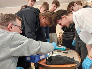 Zdjęcie w kolorze przedstawia młodzież podczas zajęć w pracowni technika kryminalistyki. Uczniowie sami wykonują odbitki palców.