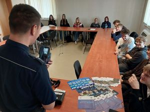 Zdjęcie w kolorze przedstawia młodzież podczas prelekcji z policjantem ruchu drogowego.