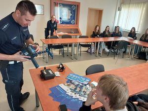Zdjęcie w kolorze przedstawia młodzież podczas prelekcji z policjantem ruchu drogowego.
