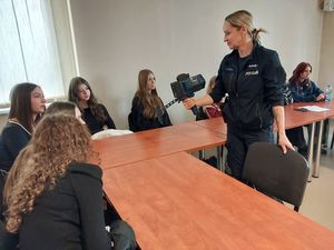 Zdjęcie w kolorze przedstawia młodzież podczas prelekcji z policjantem ruchu drogowego.