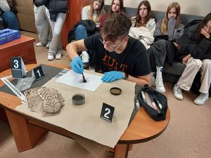 Zdjęcie w kolorze uczestnik zajęć ujawnia ślady na kartce papieru przy pomocy pędzla magnetycznego.