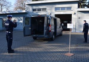 Zdjęcie w kolorze przedstawia stanowisko do przyjęcia pojazdów obsługiwane przez policjanta, który fotografuje pojazd typu bus.