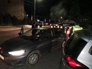 Zdjęcie w kolorze przedstawia w porze nocnej na pierwszym planie dwa pojazdy za którymi stoją funkcjonariusze policji w kamizelkach odblaskowych.