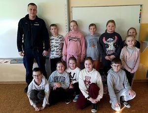 Zdjęcie w kolorze przedstawia dzieci pozujące do zdjęcia z policjantem.