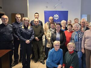 Zdjęcie w kolorze przedstawia seniorów pozujących do wspólnego zdjęcia z policjantami.
