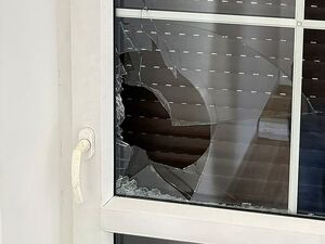 Zdjęcie w kolorze przedstawia fragment drzwi z rozbita szybą.