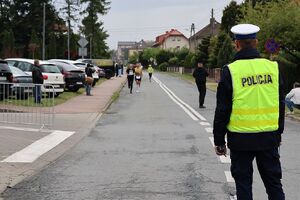 Zdjęcie w kolorze przedstawia policjanta, który zabezpiecza peleton