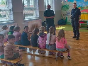Zdjęcie w kolorze przedstawia spotkanie dzieci z policjantami w sali gimnastycznej.