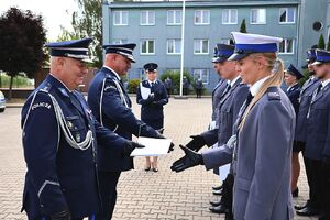 Zdjęcie w kolorze przedstawia pełniącego obowiązki Komendanta Powiatowego Policji w Oleśnie oraz Zastępcę Komendanta Wojewódzkiego Policji w Opolu podczas wręczania   policjantom nominacji na wyższe stopnie.