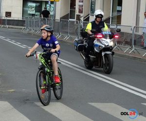 Policjant na motocyklu jedzie pilotuje młodego uczestnika wyścigu kolarskiego