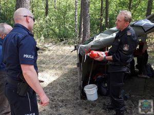 Strażak z Państwowej Straży Pożarnej w Oleśnie sprawdza atest gaśnicy na wyposażeniu jednego z namiotów.