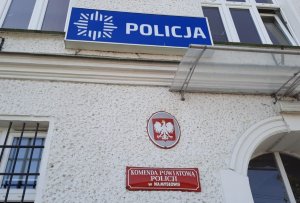 Biały budynek z logiem policji i tablicą informacyjną.