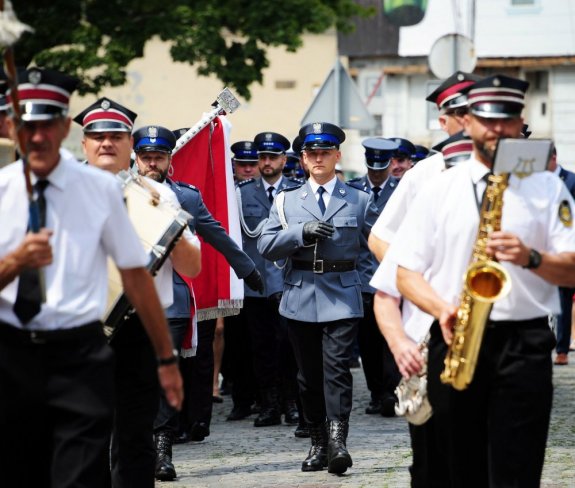 Orkiestra dęta idzie ulicami miasta, za nią oddział policjantów w mundurach galowych.
