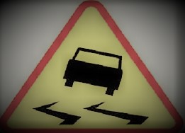 Znak drogowy ostrzegający o śliskiej nawierzchni na drodze.