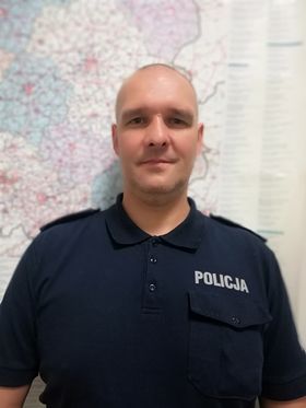 Mężczyzna z ogoloną głową pozuje na tle mapy.