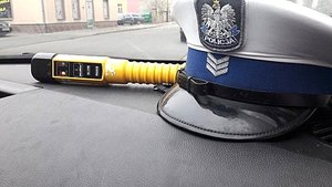 policyjna czapka i urządzenie do badania trzeźwości leżące na podszybiu w radiowozie