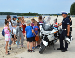 policjant stojący przy motocyklu obok grupa dzieci