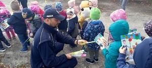 policjant rozdający opaski dzieciom