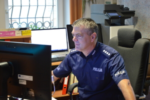 policjant w mundurze siedzący przed monitorem komputera