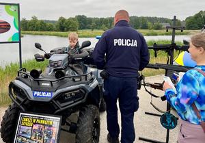 policjant pokazuje sprzęt policyjny dziecku siedzącemu na policyjnym qadzie