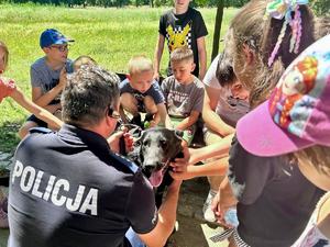 dzieci głaszczą policyjnego psa, obok policjant przewodnik