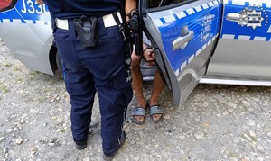 nogi policjanta i zatrzymanego obok radiowozu