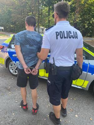 zatrzymany mężczyzna wraz z policjantem przy radiowozie