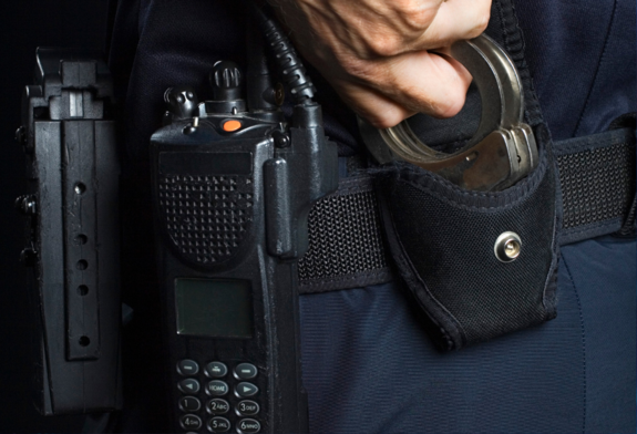elementy wyposażenia policjanta na pasie biodrowym - kajdanki, radiostacja