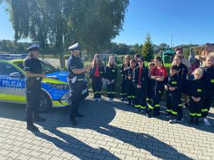 Policjanci przy radiowozie z dziećmi