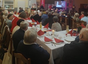 mieszkańcy przy stołach i policjant