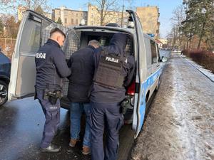 policjanci wsadzający mężczyznę do radiowozu