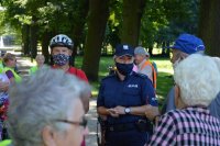 seniorzy ubrani w kamizelki odblaskowe uczestniczący w spotkaniu z policjantami w parku miejskim w Kluczborku