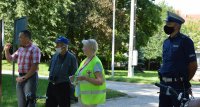 seniorzy ubrani w kamizelki odblaskowe uczestniczący w spotkaniu z policjantami w parku miejskim w Kluczborku