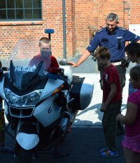 dziecko siedzące na maotocyklu po0licyjny obok stojący policjant ruchu drogowego