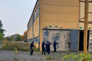 Zdjęcie przedstawia policjantów w trakcie szkolenia, wykonujących ćwiczenia przed budynkiem.